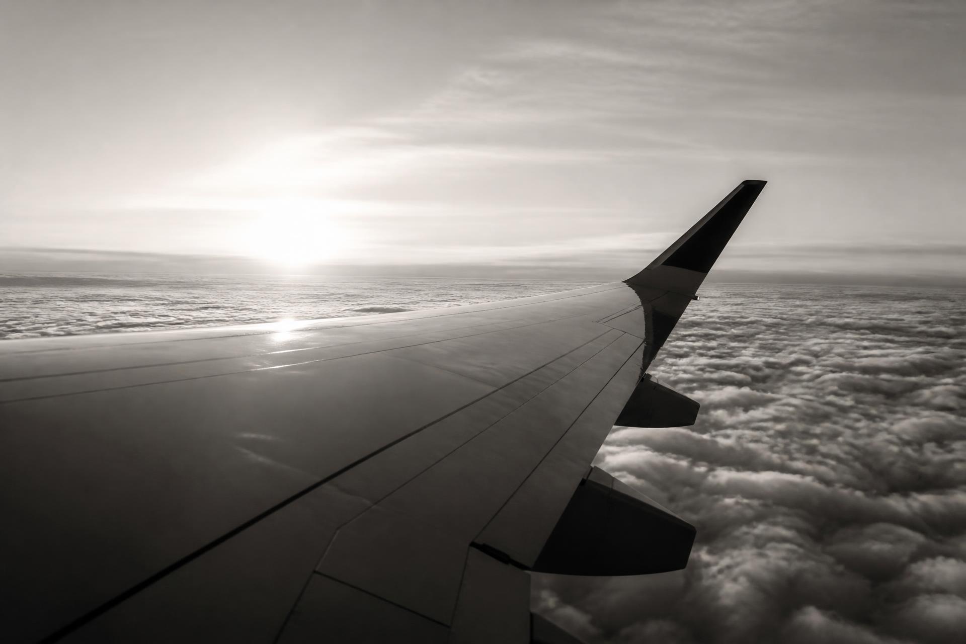 Airplane wing above the clouds at sunrise